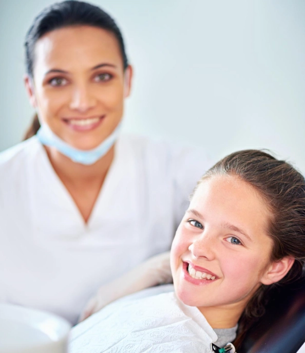 Clinician and child smiling in a dental chair during a dental appointment.