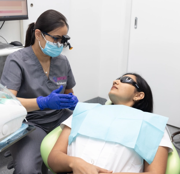 Clinician consulting with a patient seated in a dental chair before treatment.