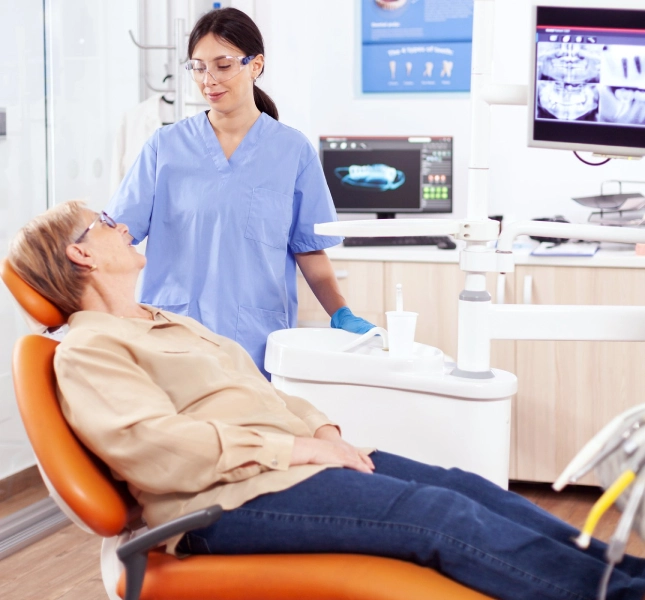 Clinician speaking with a person seated in a dental chair during a dental consultation.