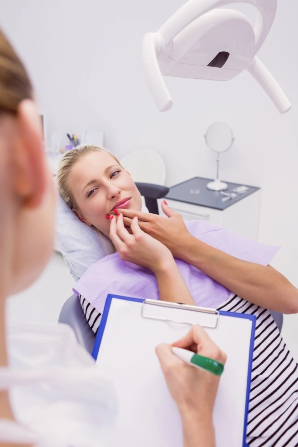 Clinician discussing a dental model with a person seated in a dental chair.
