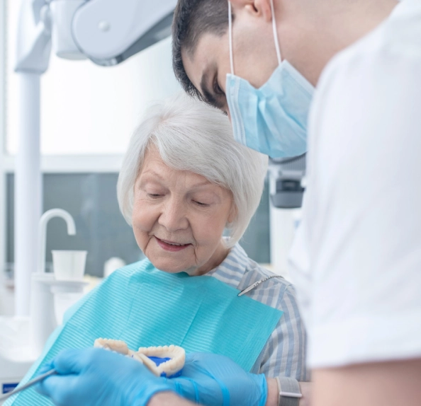 clinician holding dental model older woman