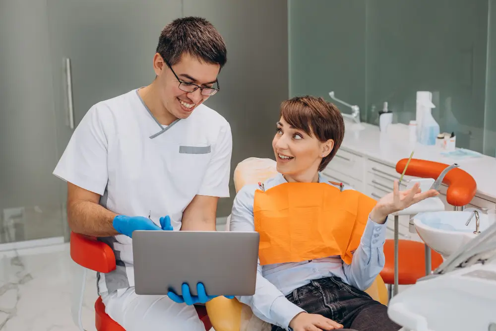 Clinician showing a laptop to a person in a dental chair