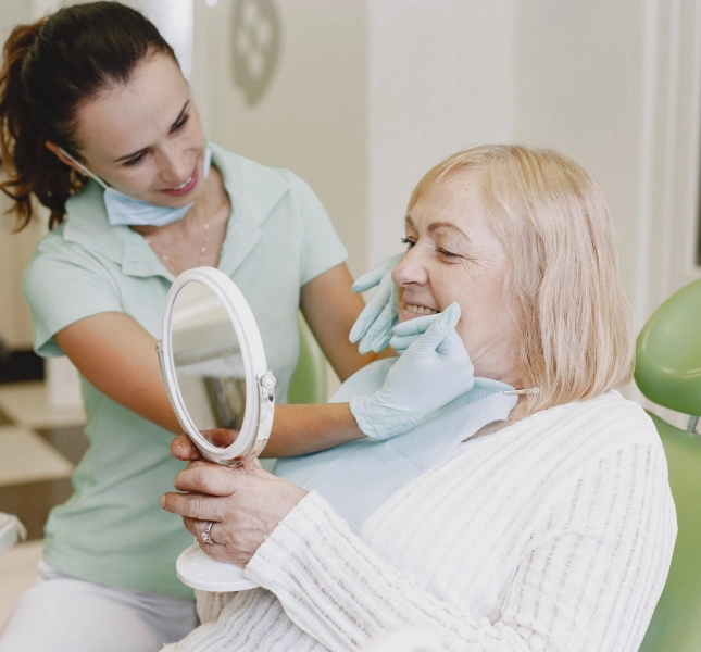 Clinician showing a person their smile with a handheld mirror during a dental appointment.