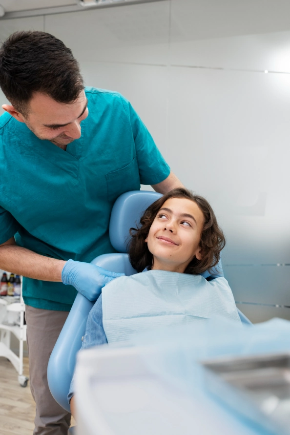 Clinician speaking with a child seated in a dental chair before a dental examination.
