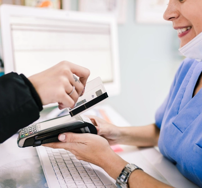 Person making a contactless card payment at a dental clinic reception.