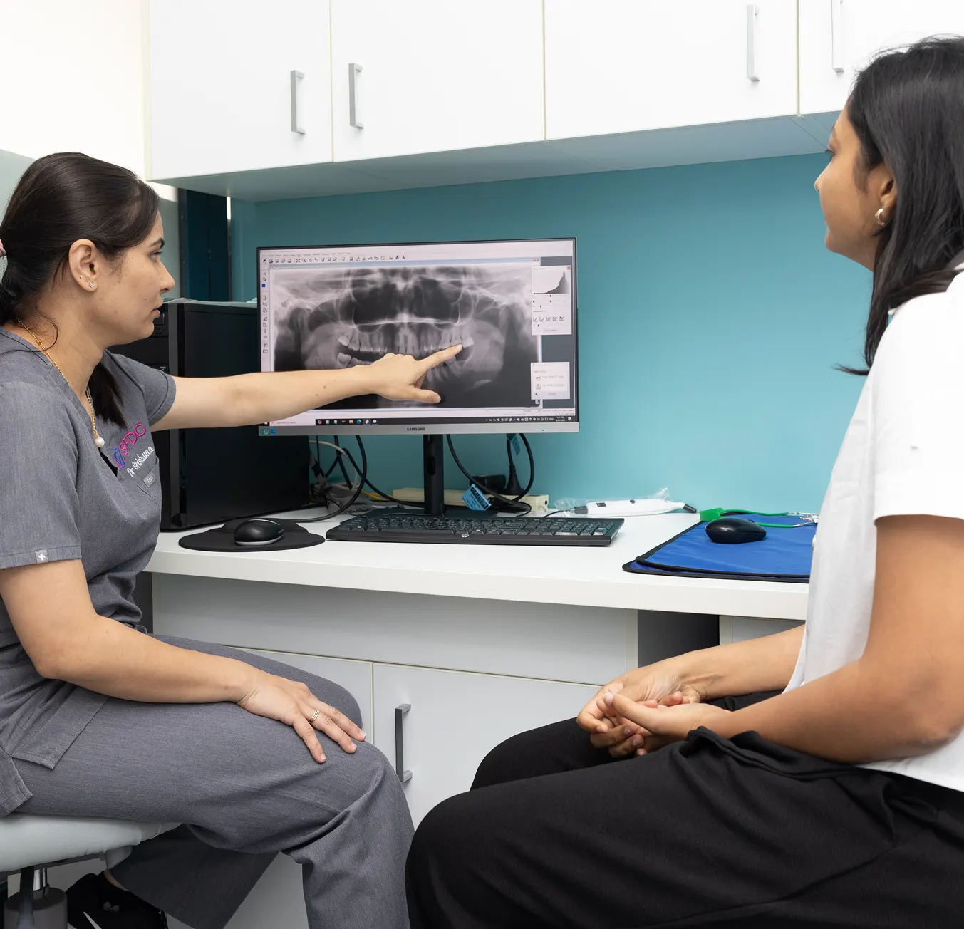 Dentist pointing to a dental X-ray on a computer screen