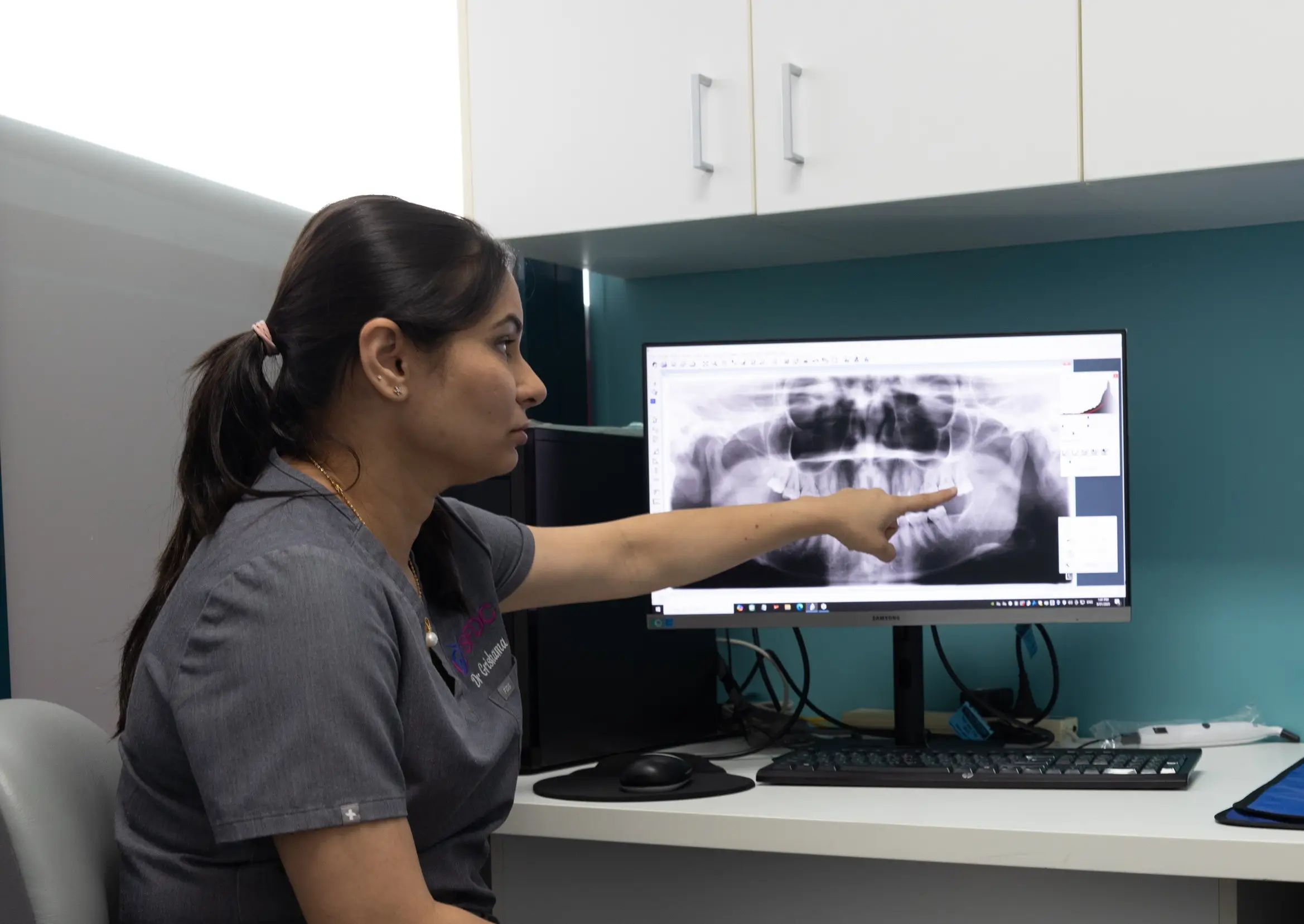 Dentist reviewing a panoramic dental X-ray on a computer monitor during a patient consultation
