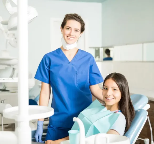 Dentist standing beside a smiling young patient in the dental chair