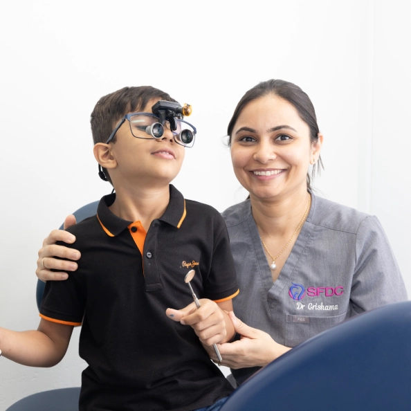 Dr Grishama from SFDC sitting with a boy wearing dental loupes in a treatment room