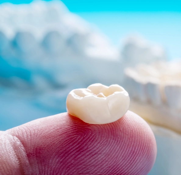 finger holding ceramic dental crown plaster model