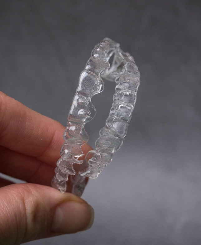 Hand holding two transparent plastic dental aligners