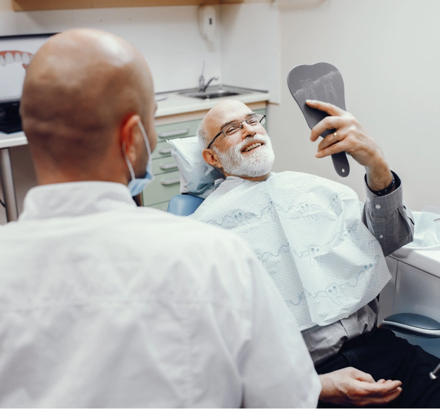man in dental chair holding hand mirror clinician