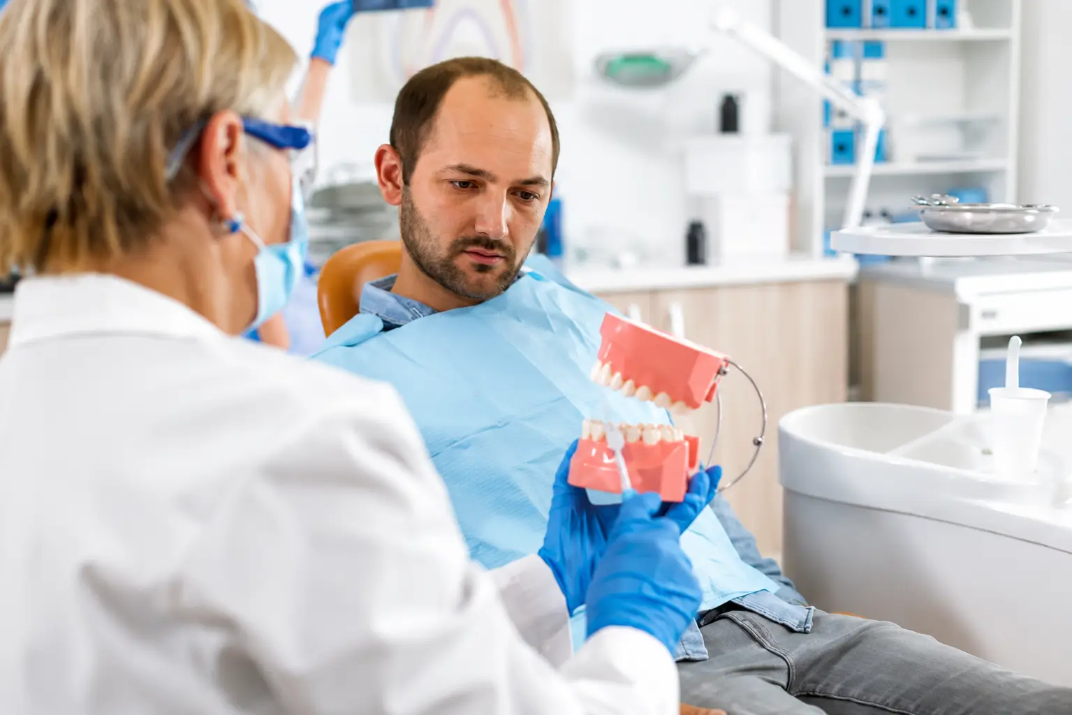 Dentist discussing oral health and treatment using a dental model during a consultation