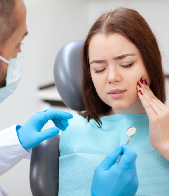 Patient holding their jaw during a dental consultation for tooth pain.