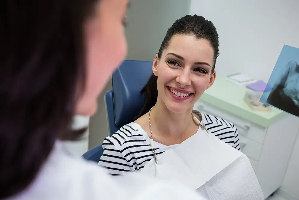 Female patient smiling while discussing her dental treatment plan with the dentist