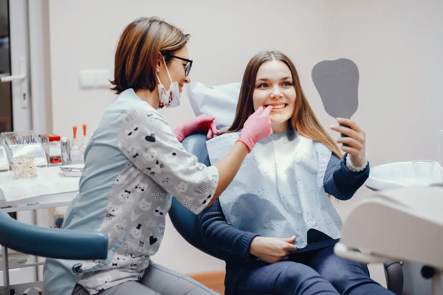 Patient checking her smile in a mirror after a dental consultation