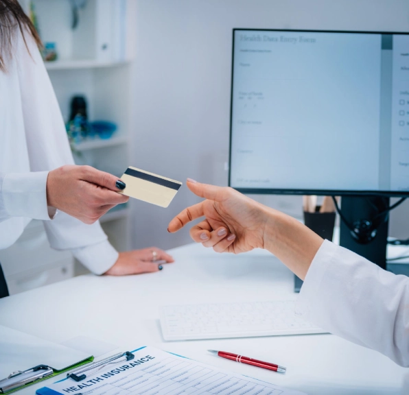 Person handing a payment card across a clinic reception desk.