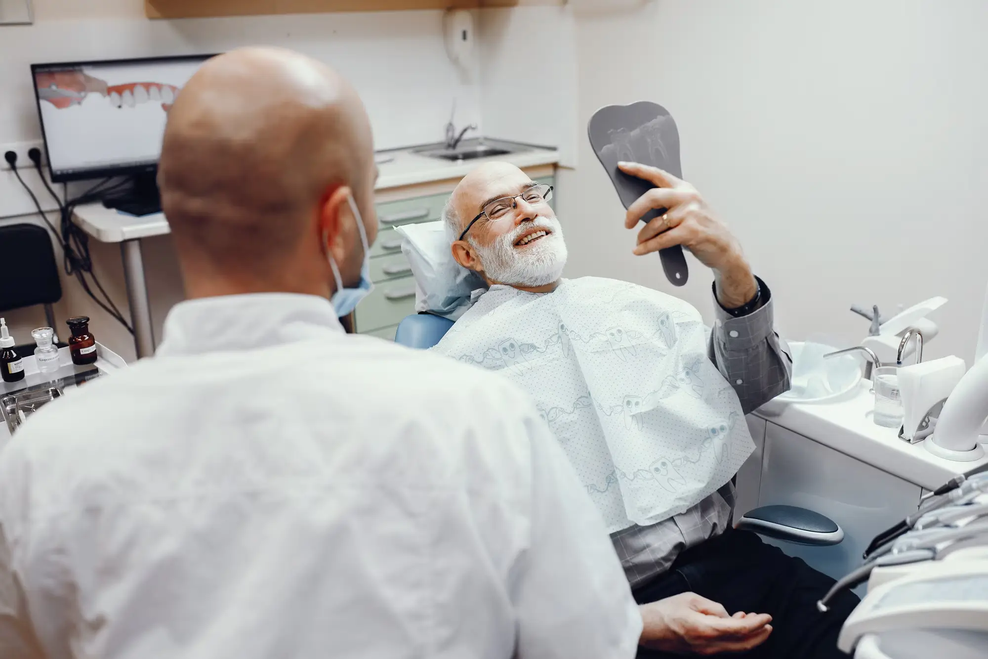 Person in a dental chair holding a hand mirror