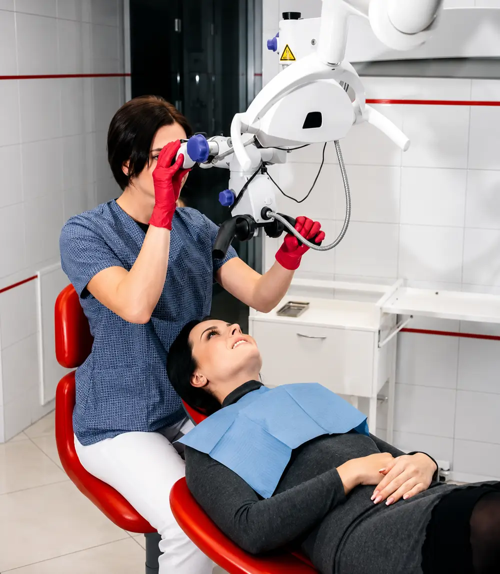 Dentist using a dental microscope to examine a patient during a root canal treatment consultation
