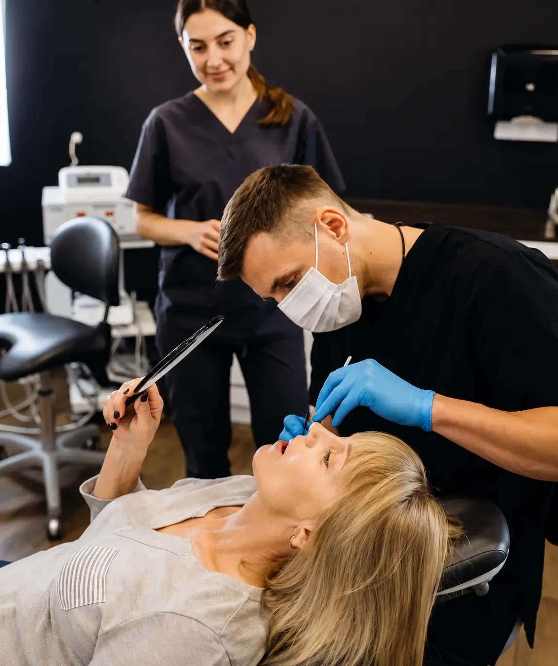 Dentist performing a routine dental check-up while discussing treatment with a patient