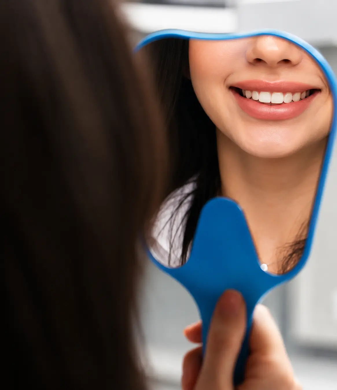Woman smiling while checking her smile after cosmetic dentistry treatment