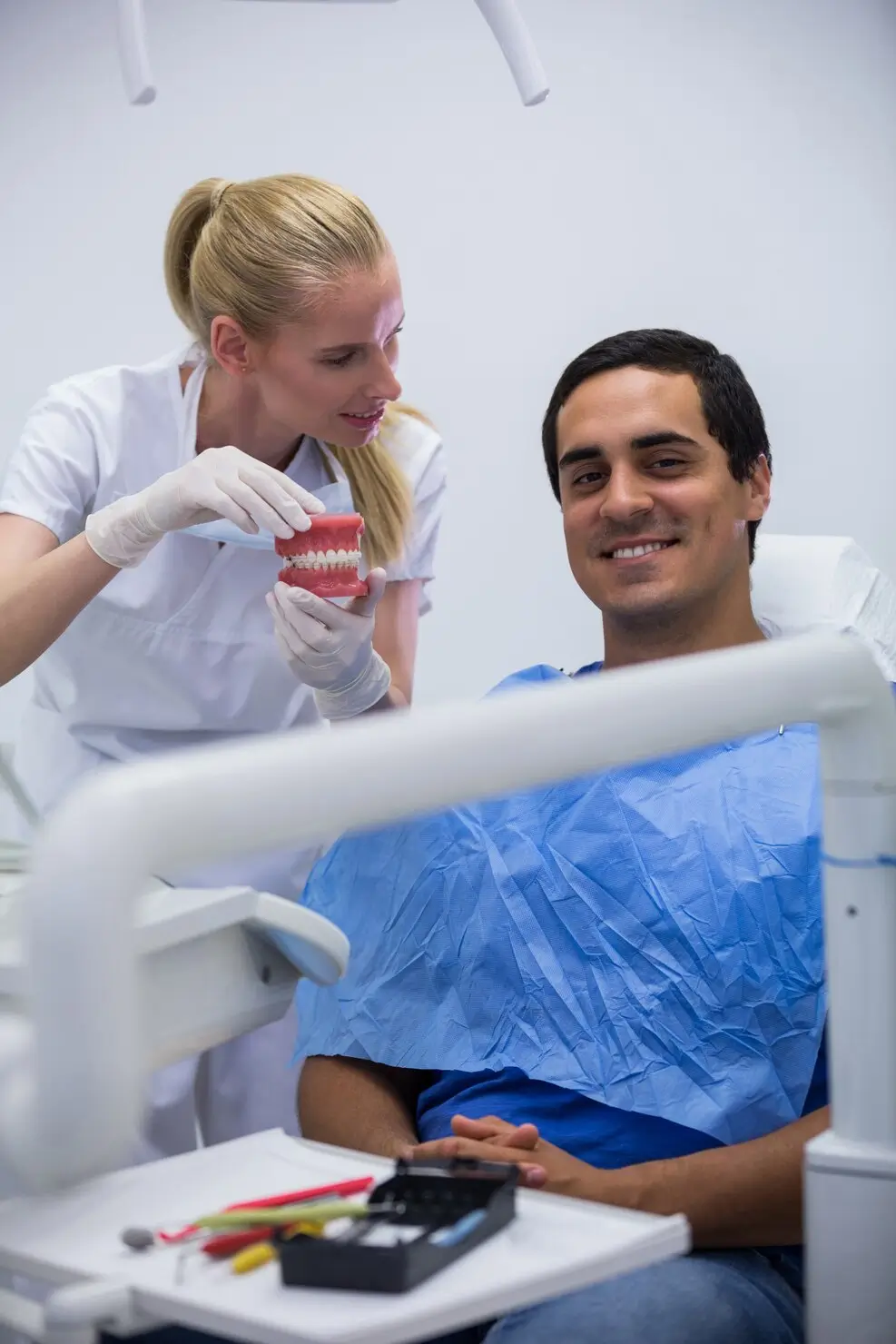 Dentist explaining a tooth extraction procedure using a dental model
