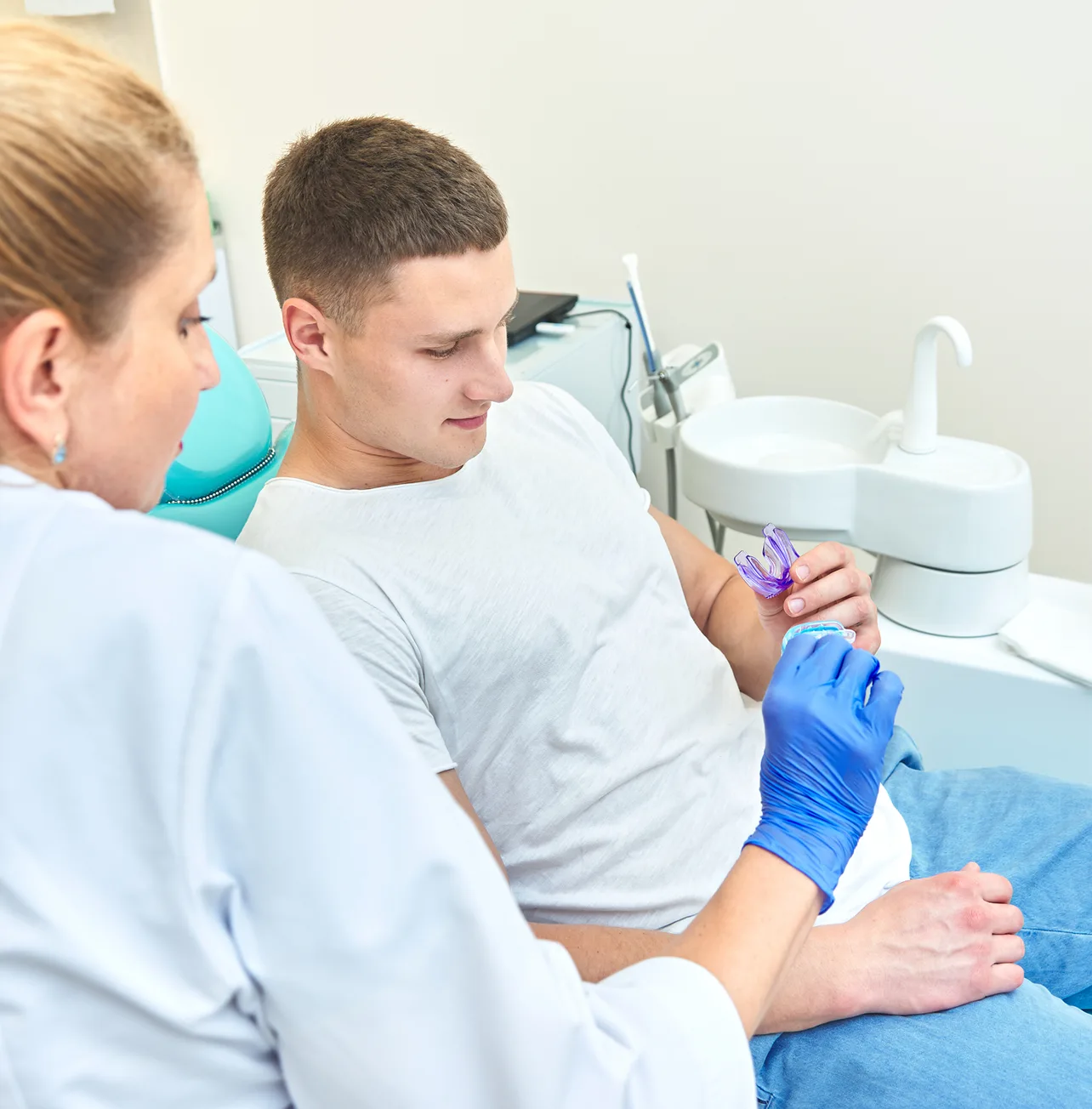 Dentist showing a mouthguard to a seated man