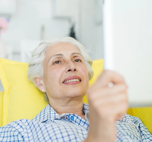 Older woman reclining in a chair with her hand raised