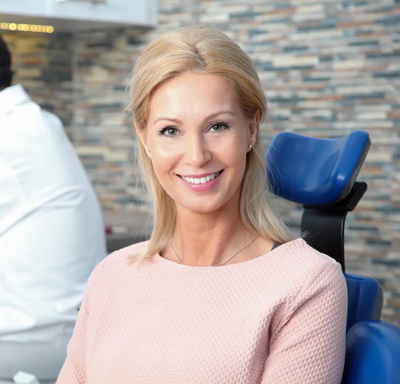 Smiling woman sitting in a dental chair after root canal treatment