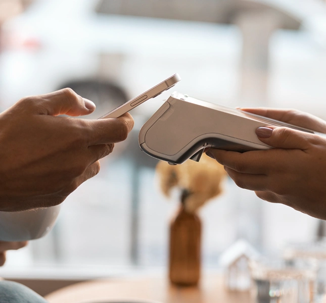 Person holding a smartphone near a contactless payment terminal