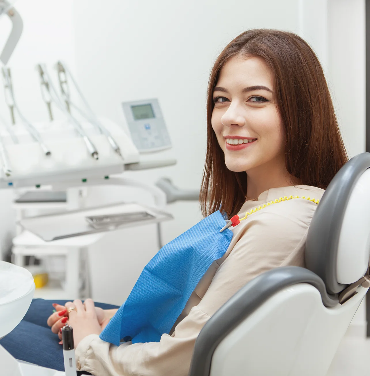 Woman seated comfortably in a dental chair wearing a blue bib