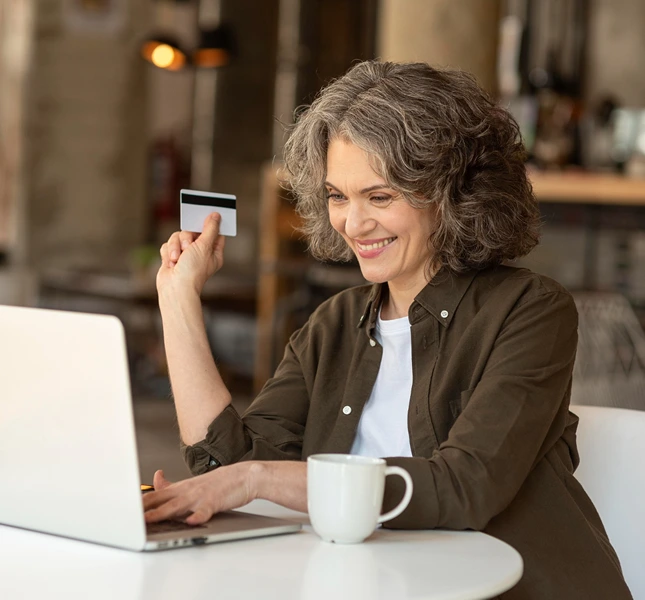 Woman using a laptop while holding a payment card